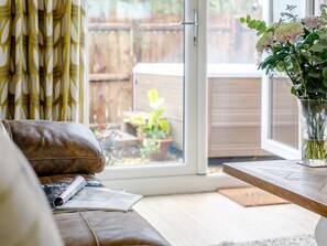 A living room with a leather sofa, a glass vase with flowers, and a wooden table.
