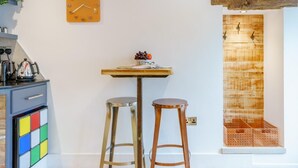 Una cucina con un tavolo di legno, due sgabelli, una sveglia e una porta in legno rustica.