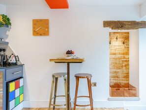 A kitchen with a wooden table, two stools, a clock, and a rustic wooden door. - 1 Bed in Skipton (oc-78576) (Skipton)