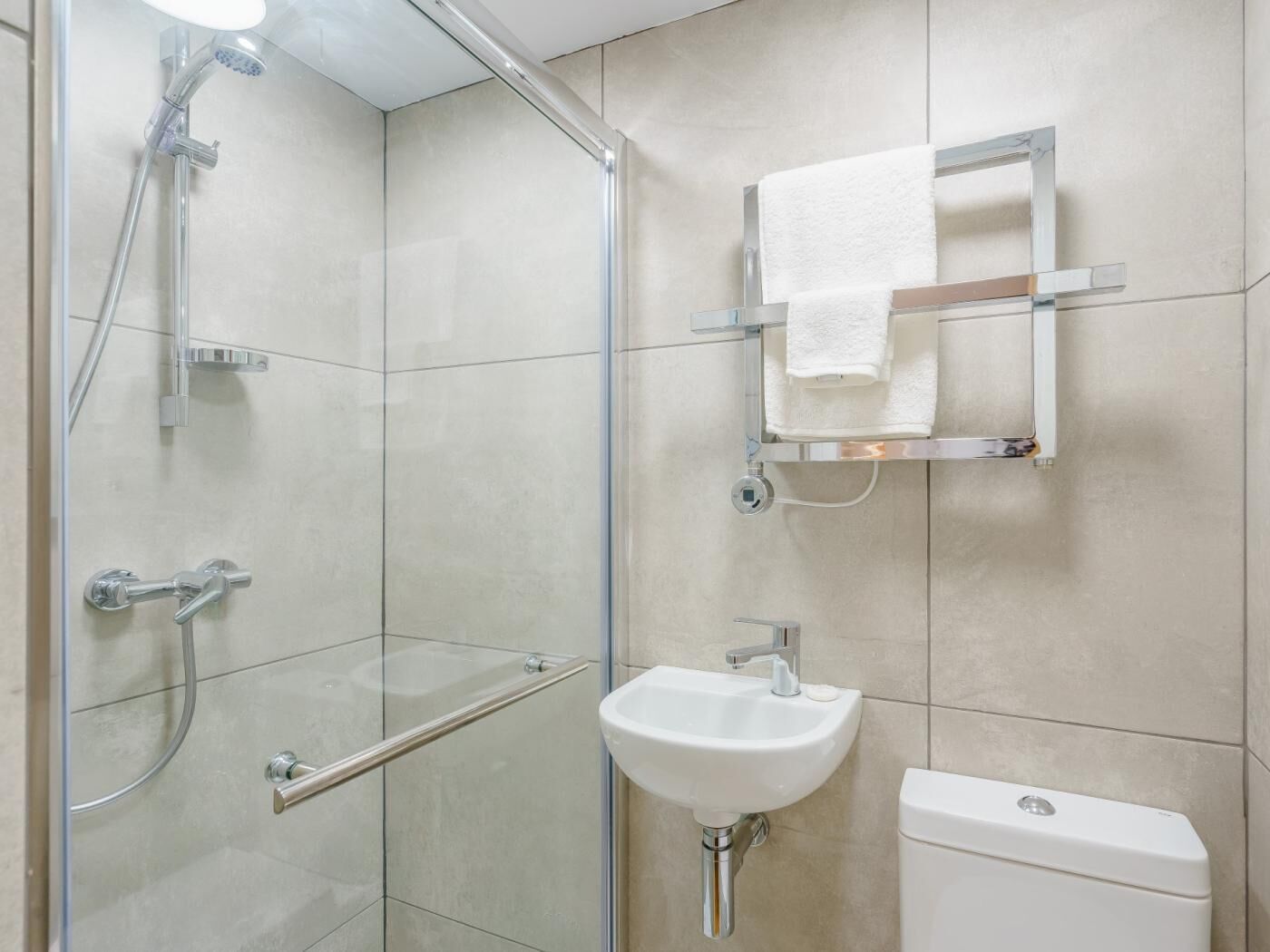 A modern bathroom with a glass shower enclosure, a white sink, and a toilet.