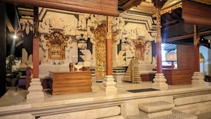 An interior with ornate carvings, a central pillar, and a wooden bench.