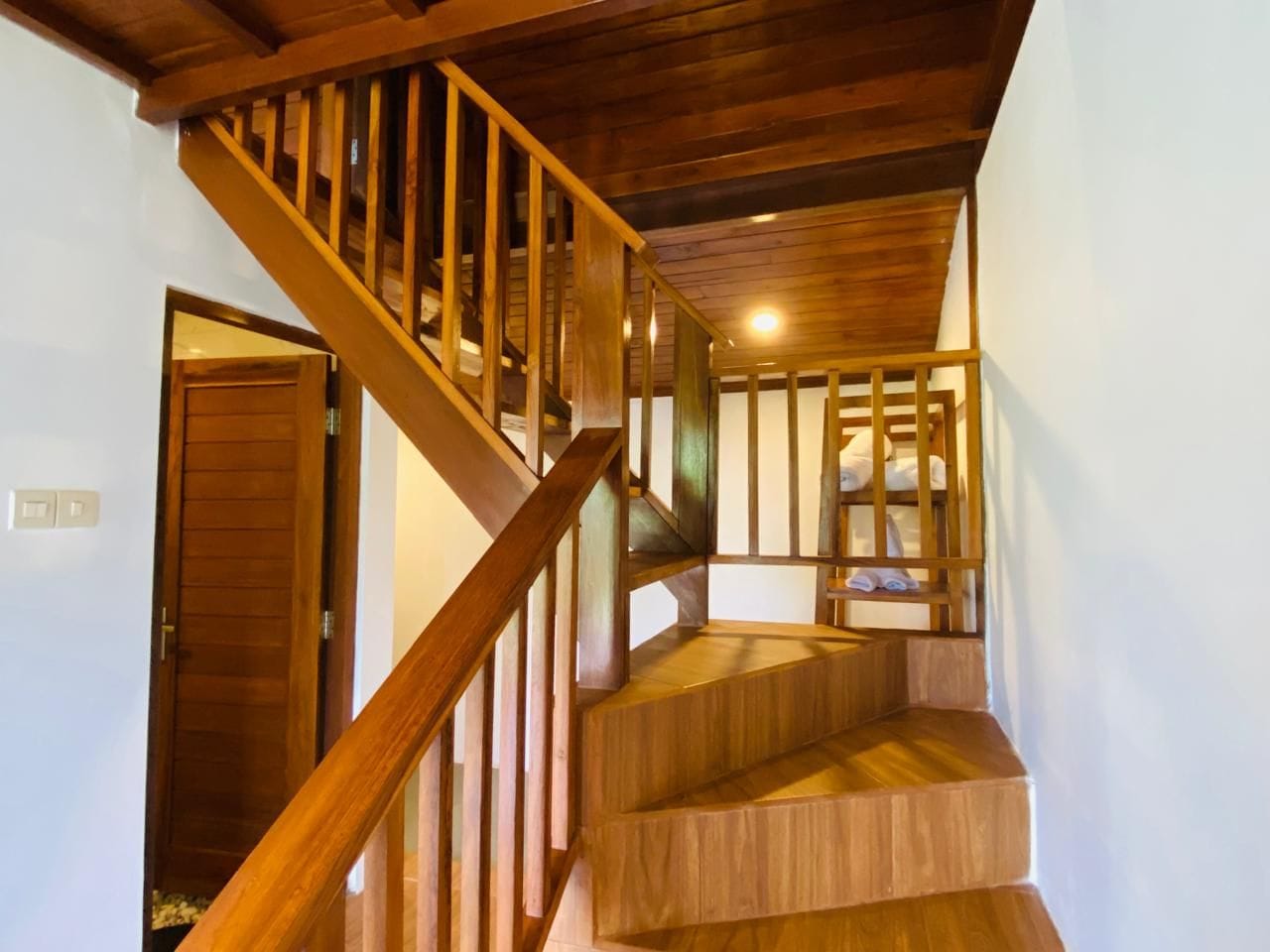 Una escalera de madera con barandilla que lleva a un piso superior.