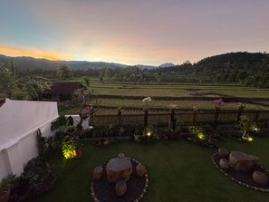 A landscaped garden with a view of terraced fields and a white building.