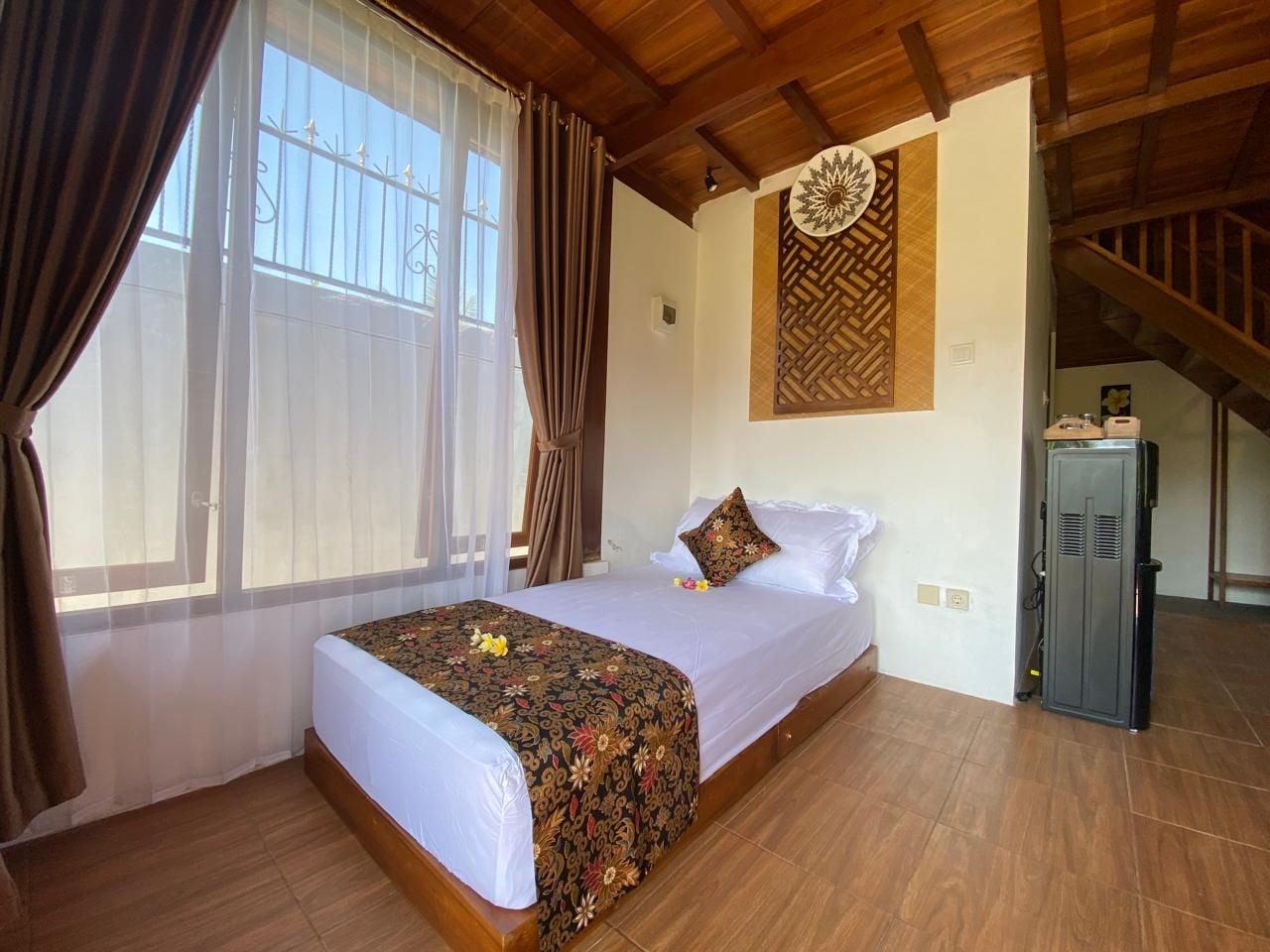 A bedroom with a bed, curtains, a decorative wall panel, and a wardrobe.
