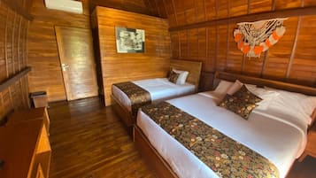 A room with two beds, wooden walls, a wooden floor, and a ceiling fan.