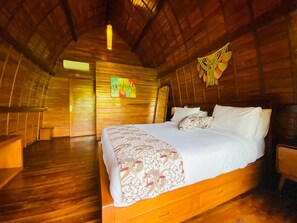 A cozy, wooden interior with a large bed, a wooden bench, and a colorful painting on the wall. - Sarenmas Cottage Munduk (Munduk)