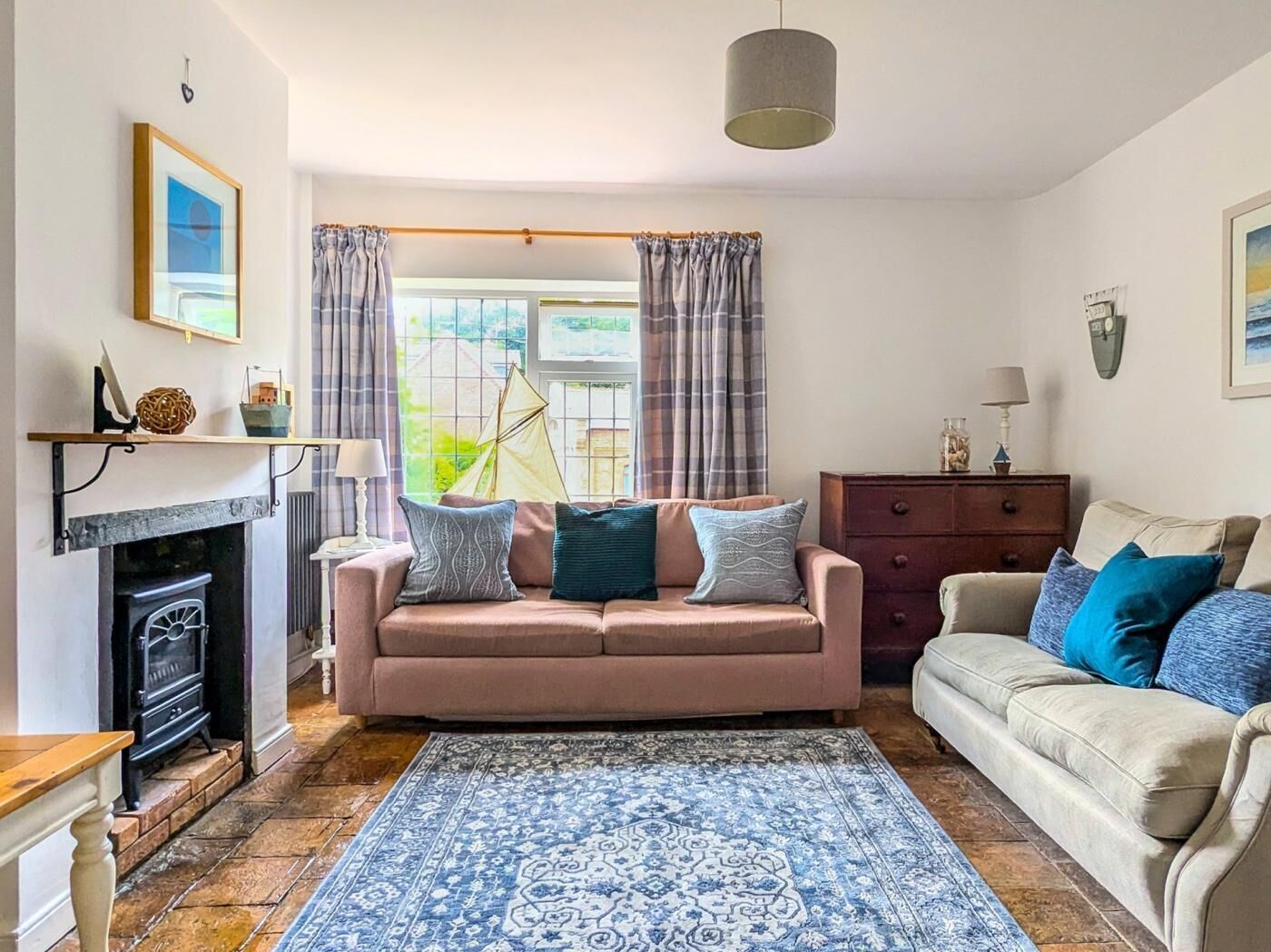 A cozy living room with a fireplace, two sofas, a patterned rug, and a view of the outdoors.