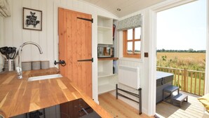 A kitchen with a wooden door, a window, and a view of the outdoors. - 1 Bed in Market Rasen (oc-83847) (Faldingworth)
