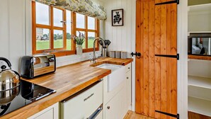 A kitchen with wooden countertops, a sink, a stove, and a refrigerator. There are large windows with a view of greenery outside. - 1 Bed in Market Rasen (oc-83847) (Faldingworth)
