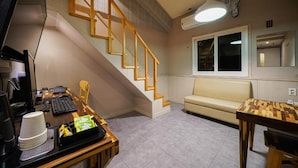 A room with a desk, computer, chair, and a staircase.