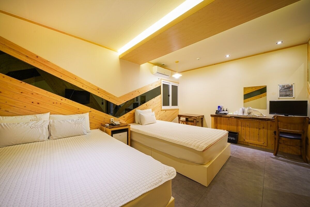 Una camera da letto con due letti, una scrivania, una sedia e un angolo cottura.