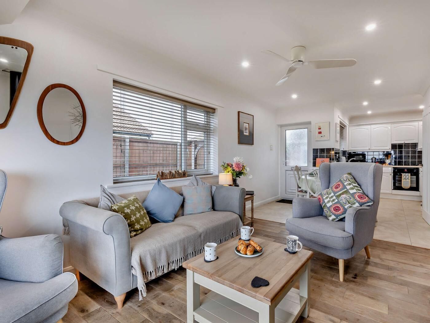 Een moderne woonkamer met een bank, fauteuils, een salontafel en een eethoek.