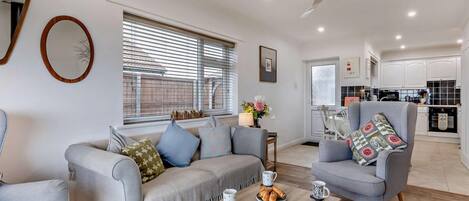 Een moderne woonkamer met een bank, fauteuils, een salontafel en een eethoek.