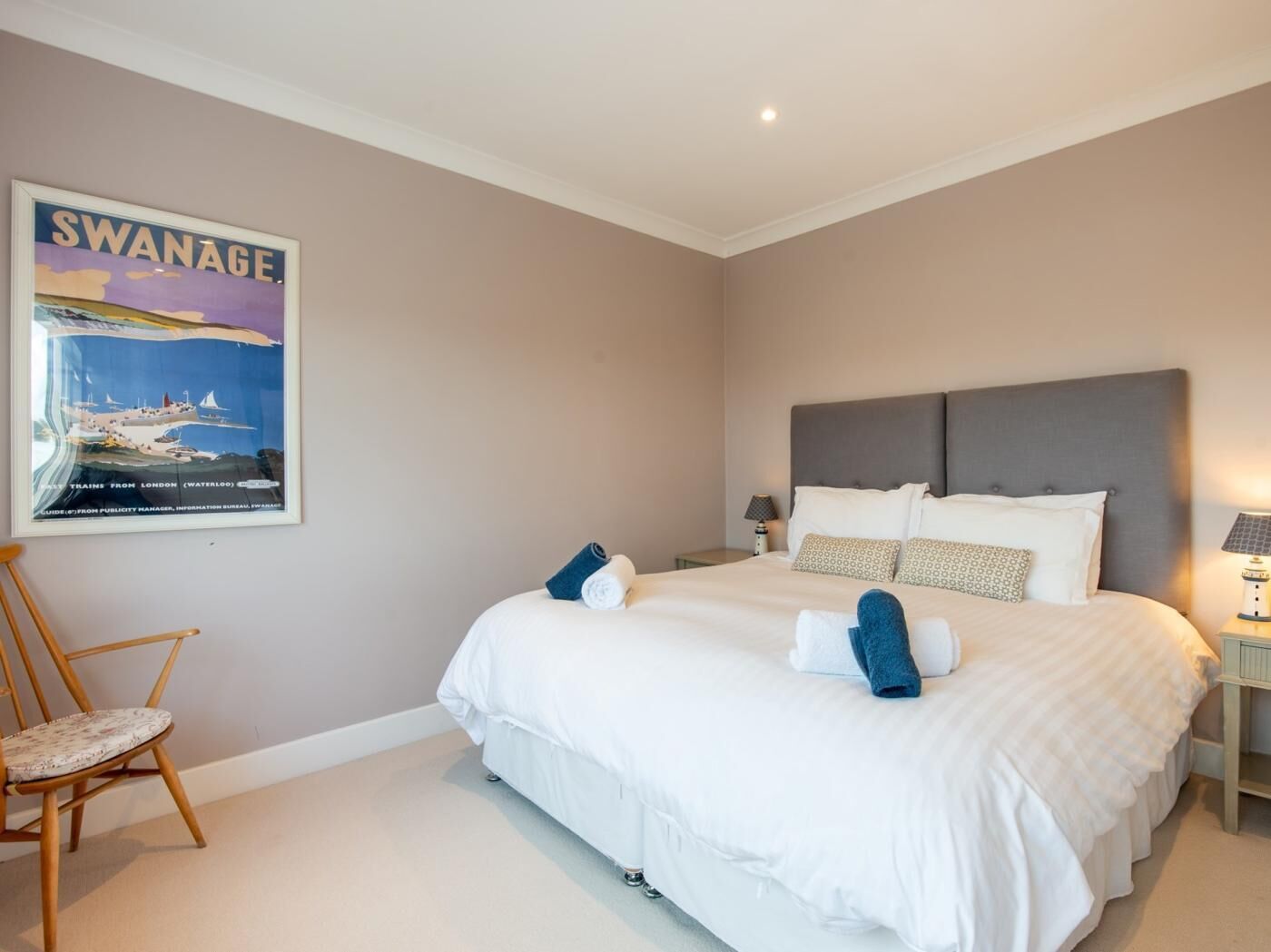 Une chambre d’hôtel avec un grand lit, une chaise, une table de chevet et une affiche au mur.
