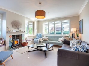 A living room with a fireplace, a sofa, a coffee table, and a chair. - 5 Bed in Swanage (oc-dc030) (Studland)