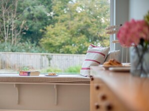 A window seat with a cushion, a book, and a plate with food. - 5 Bed in Swanage (oc-dc030) (Studland)