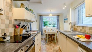 Une cuisine compacte avec un coin repas, une vue sur l’extérieur et une fenêtre équipée de stores.