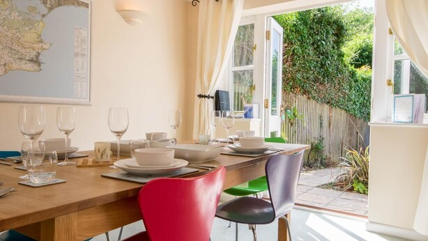 A dining area with a wooden table set for four, chairs, and a map on the wall. - 3 Bed in Swanage (oc-dc072) (Studland)