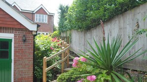 A residential garden with a wooden staircase, a green door, and a brick wall. - 3 Bed in Swanage (oc-dc072) (Studland)