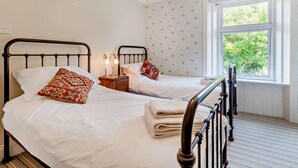 A bedroom with two beds, a window with a view, and a bedside table with lamps. - 3 Bed in Portland (oc-dc031) (Portland)