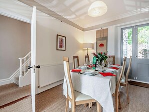 A dining area with a table set for four, a lamp, and a vase with flowers. - 3 Bed in Portland (oc-dc031) (Portland)