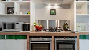 A modern kitchen with a microwave, two ovens, a gas stove, and a bowl of fruit. - 3 Bed in Portland (oc-dc031) (Portland)