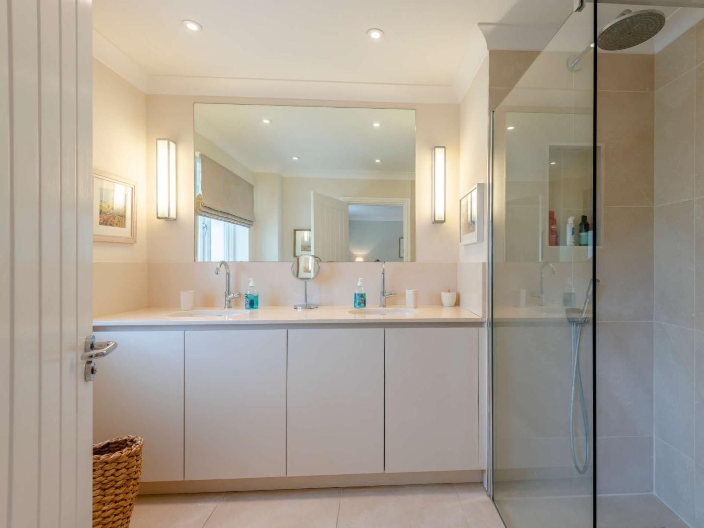 A modern bathroom with a large mirror, a shower, and a vanity with a sink.