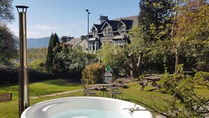 A hot tub in a garden with a house in the background. - 9 Bed in Keswick (oc-sz238) (Keswick)