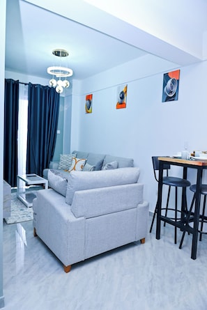 A modern room with a sofa, dining table, chairs, and artwork on the walls. - Marvelous 1-bedroom apartment in vibrant Nairobi perfect for your stay (Nairobi)