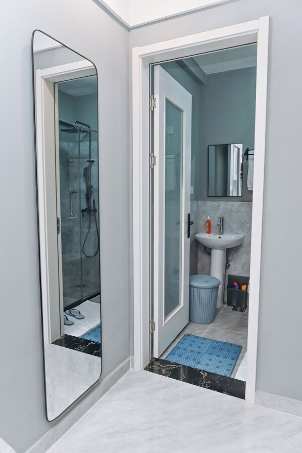 Une salle de bain avec une douche à parois de verre, un lavabo et un miroir.