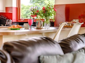 Eine Küchenzeile mit einem Esstisch, einem Stuhl, einer Vase mit Blumen und einem Croissant auf dem Tisch.
