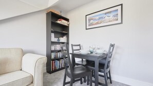 Una habitación con un sofá, una mesa de comedor con sillas, una estantería y un cuadro en la pared.