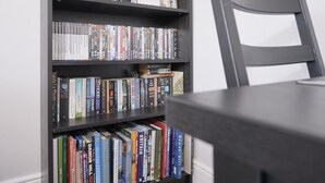 Una estantería con varios libros, una silla y una mesa.