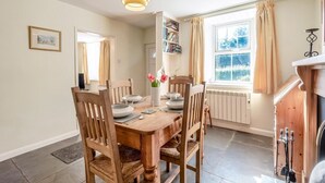 A dining area with a wooden table, chairs, a vase with flowers, a bookshelf, and a window with curtains. - 2 Bed in Workington (oc-sz331) (Lamplugh)