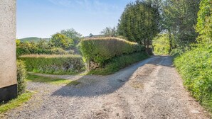 A gravel path leading through a rural landscape with a stone wall and dense shrubbery. - 2 Bed in Workington (oc-sz331) (Lamplugh)