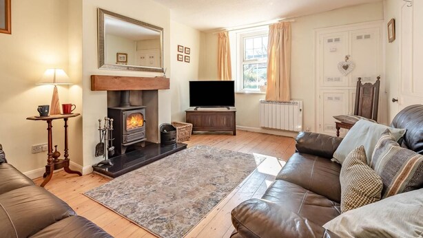 A living room with a fireplace, a sofa, a television, and a large mirror. - 2 Bed in Workington (oc-sz331) (Lamplugh)