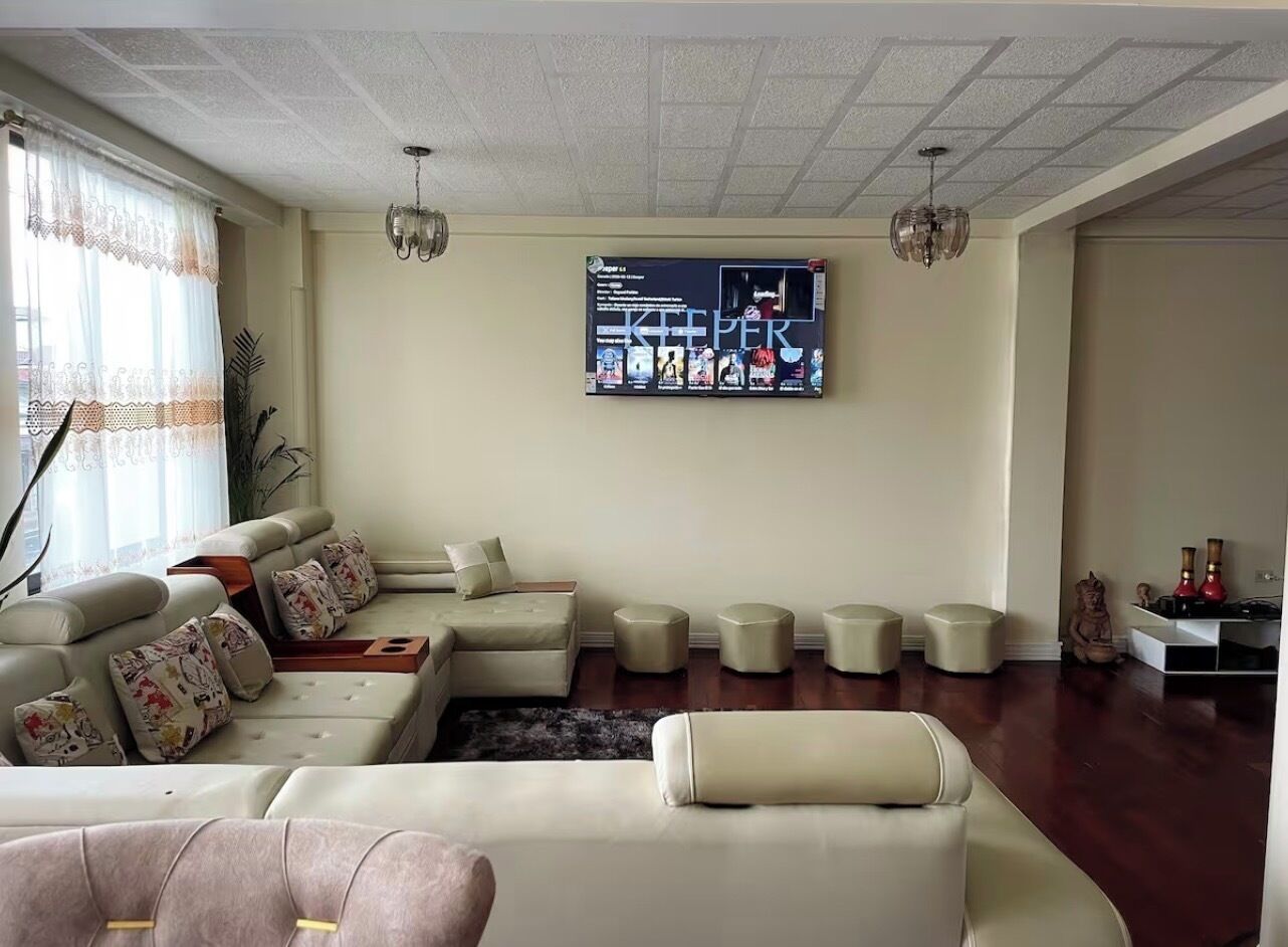 Un salon comprenant un ensemble de canapés, un téléviseur à écran plat et un élément décoratif mural.