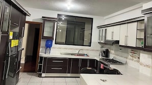 Eine moderne Küche mit dunklen Schränken, einem großen Fenster und einer Spüle.