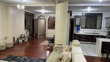 A living room with a sofa, a rug, and a kitchen area with cabinets and a sink.