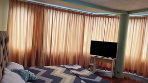 Ein Hotelzimmer mit Bett, Fernseher auf einem Tisch und Vorhängen.