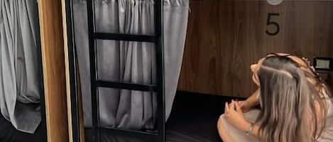 A bunk bed room with wooden walls, numbered bunks, and curtains.