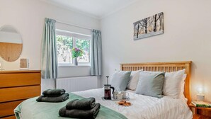 A bedroom with a bed, a bedside table with a lamp, a window with curtains, a radiator, and a wall-mounted picture. - 2 Bed in Ashbourne (oc-85571) (Ashbourne)