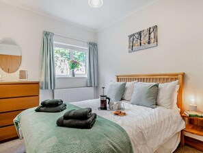 A bedroom with a bed, a bedside table with a lamp, a window with curtains, a radiator, and a wall-mounted picture. - 2 Bed in Ashbourne (oc-85571) (Ashbourne)