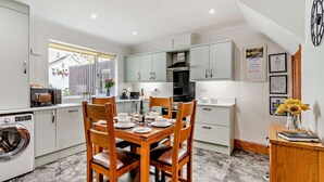 A compact kitchen with a dining area, a washing machine, and a view of the outside. - 2 Bed in Ashbourne (oc-85571) (Ashbourne)