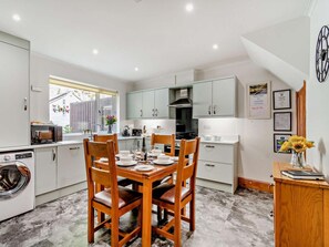 A compact kitchen with a dining area, a washing machine, and a view of the outside. - 2 Bed in Ashbourne (oc-85571) (Ashbourne)