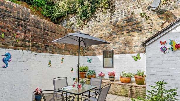 A patio with a table and chairs, surrounded by potted plants and decorative wall art. - 2 Bed in Ashbourne (oc-85571) (Ashbourne)