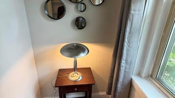 Een hoekappartement met houten vloer, een tafeltje met lamp en meerdere spiegels aan de muur.