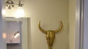 Kylpyhuone, jossa on pesuallas, wc, peili ja häränpään muotoinen koriste.