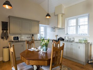 A kitchen with a dining table, chairs, a microwave, and a stove.