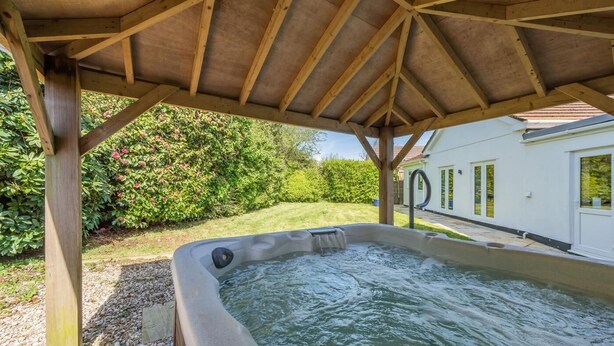 Ein Whirlpool unter einer Hollaube, im Hintergrund ein Haus.